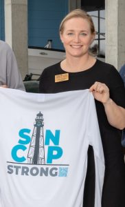 San-Cap Chamber President Calli Johnson displays SanCap Strong shirt being sold to aid recovery.